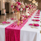 Velvet Table Runner Fuchsia on a white tablecloth with wine glasses, tall mixed pinks floral centerpieces and fuchsia napkins on top cleatr gold trimmed charger plates