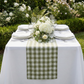 close up of the Gingham Checkered Polyester Table Runner Olive Green & White outdoor setting  with floral centerpiece and dinnerware