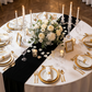 Glitter Velvet Table Runner Black  on a white round tablecloth with votive candles, roses floral centerpieces, tapered candles and wine glasses
