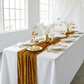 Glitter Velvet Table Runner Gold on a rectangular table with gold trimmed glass charger plates,  and gold accents