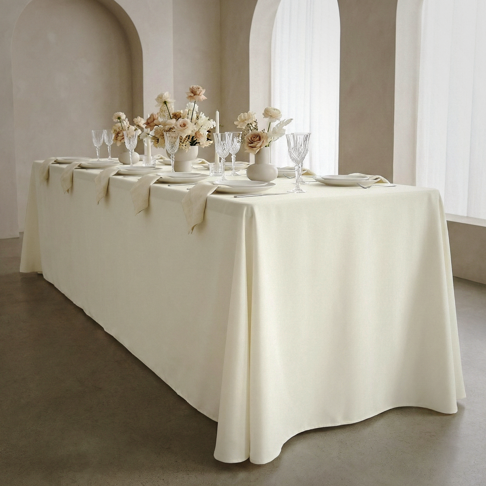 indoor table setting with the Scuba King 108"x156" Rectangular Tablecloth Ivory paired with white floral vases, ivory polyester napkins and white dinnerware 