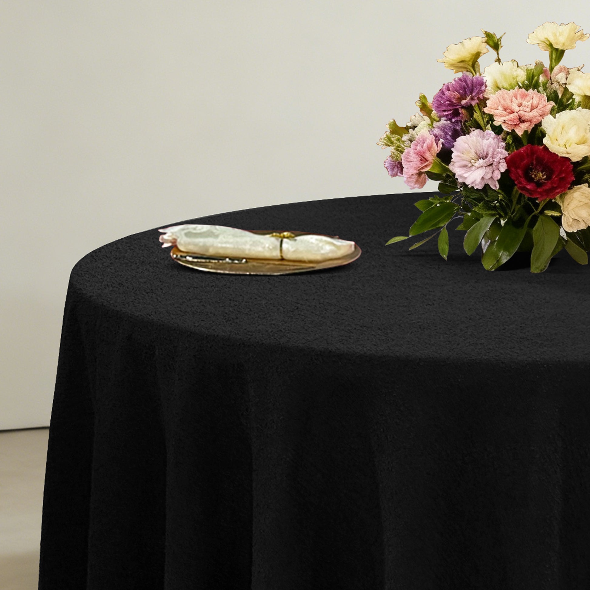 Luxury Boucle Round Tablecloth Black with floral centerpiece, gold charger plate and ivory napkin with a gold napkin ring