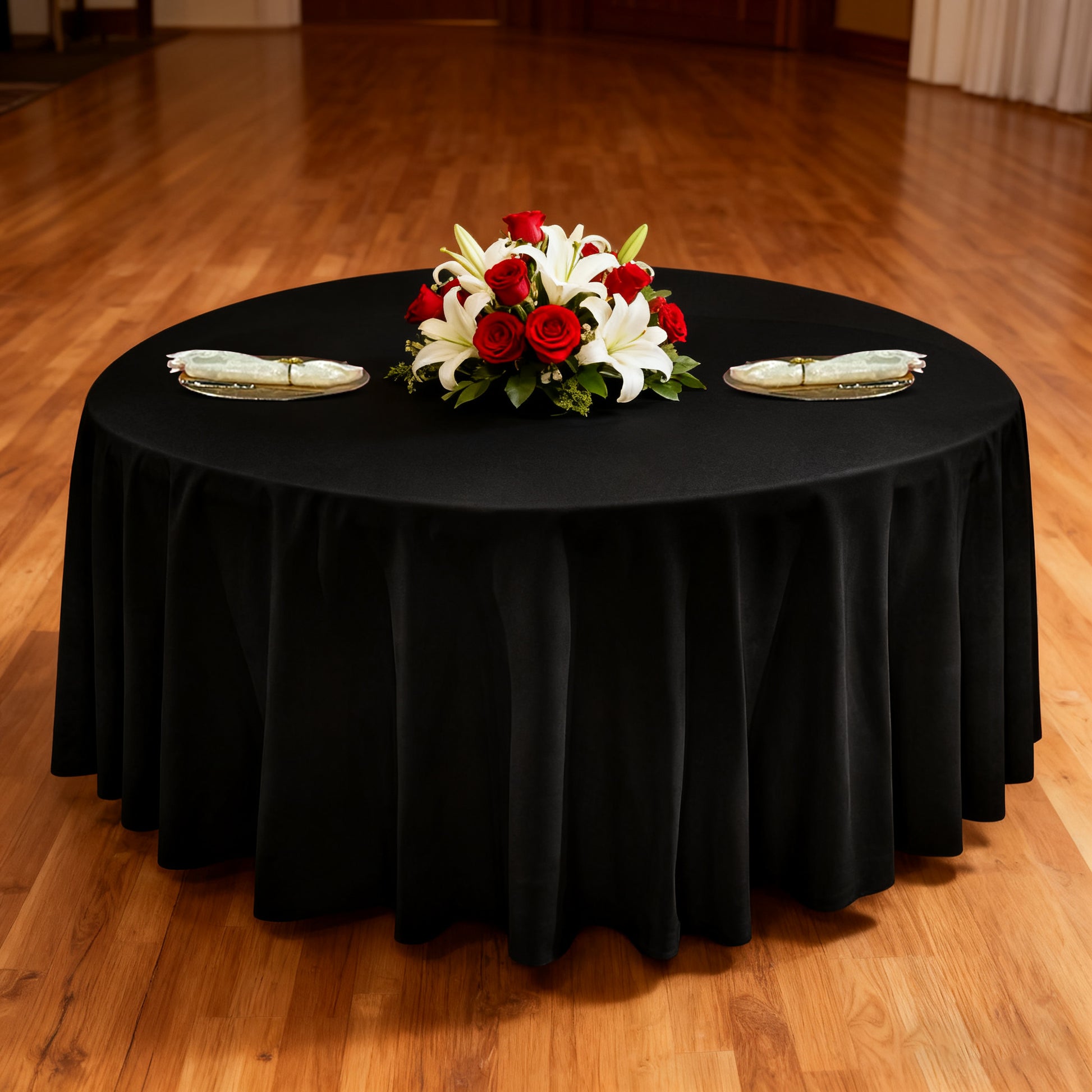 Premium 120" Round Black Spun Polyester Tablecloth with gold chargers, ivory napkins and floral centerpiece