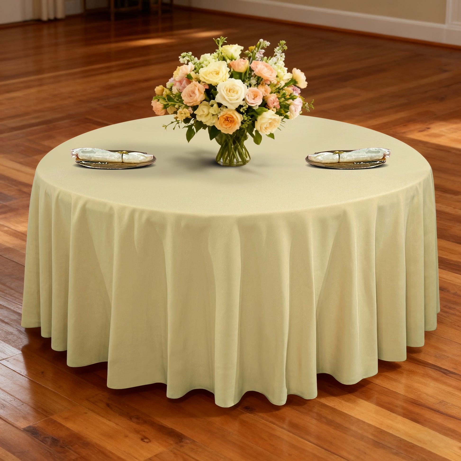 Premium 120" Round Champagne Spun Polyester Tablecloth table setting with floral centerpiece, ivory napkins and gold chargers
