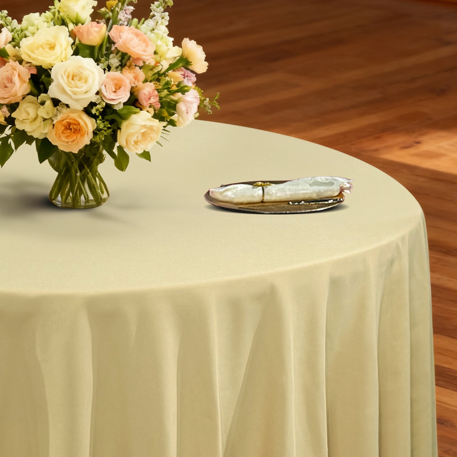 Premium 132" Round Champagne Spun Polyester Tablecloth table setting with floral centerpiece, ivory napkin and gold charger