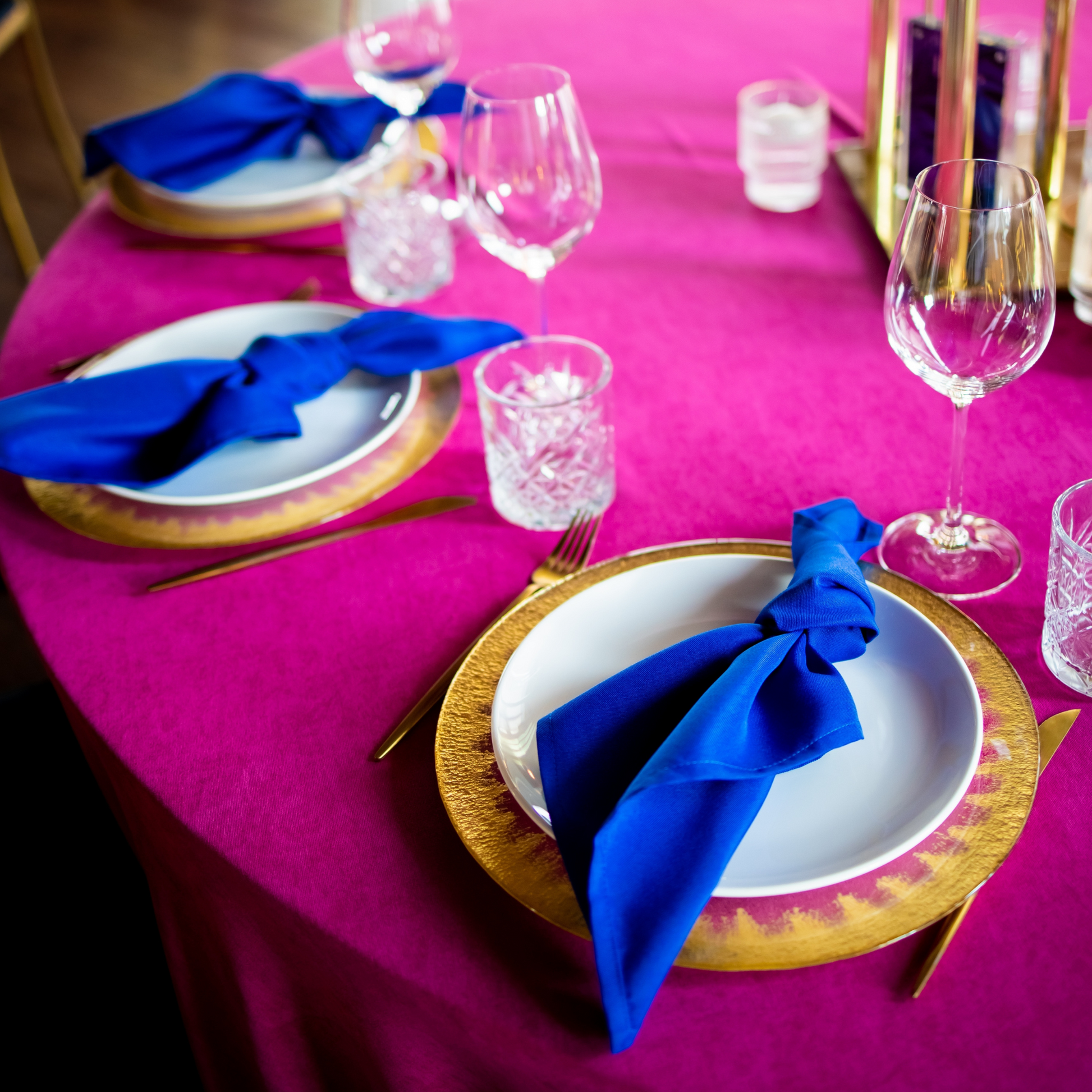 Premium Polyester Napkin 19"x19" - Royal Blue table setting with a gold charger, fuchsia tablecloth, and wine glasses