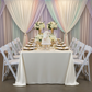 Premium Satin (Wrinkle-Resistant) King 108"x156" Rectangular Tablecloth Ivory with Garden Chairs in front of a backdrop with pastel drapes