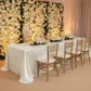 Premium Satin (Wrinkle-Resistant) King 108"x156" Rectangular Tablecloth Ivory wedding table in front a floral wall backdrop
