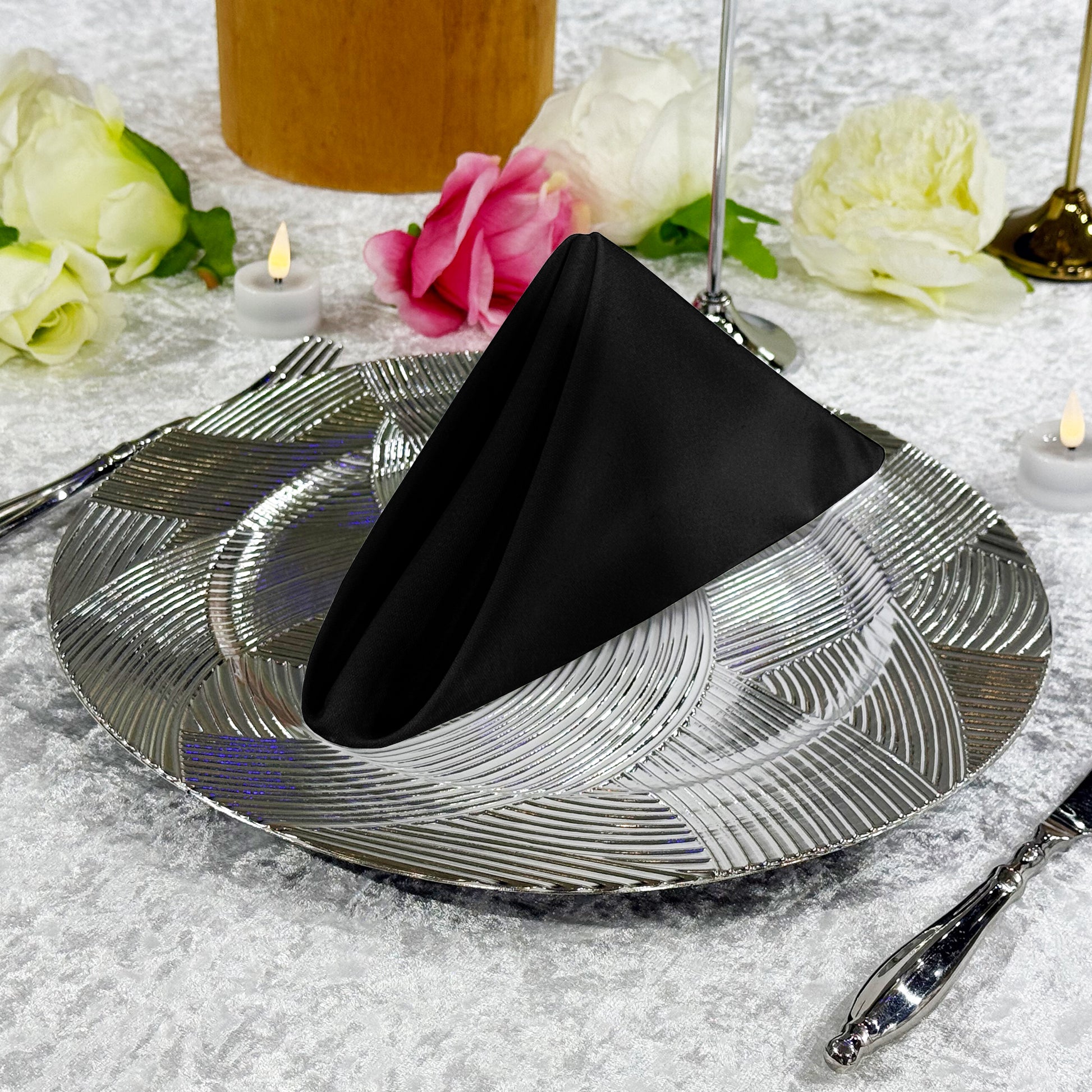 Premium Spun Polyester Napkin 20"x20" Black triangle fold ontop a silver charger plate