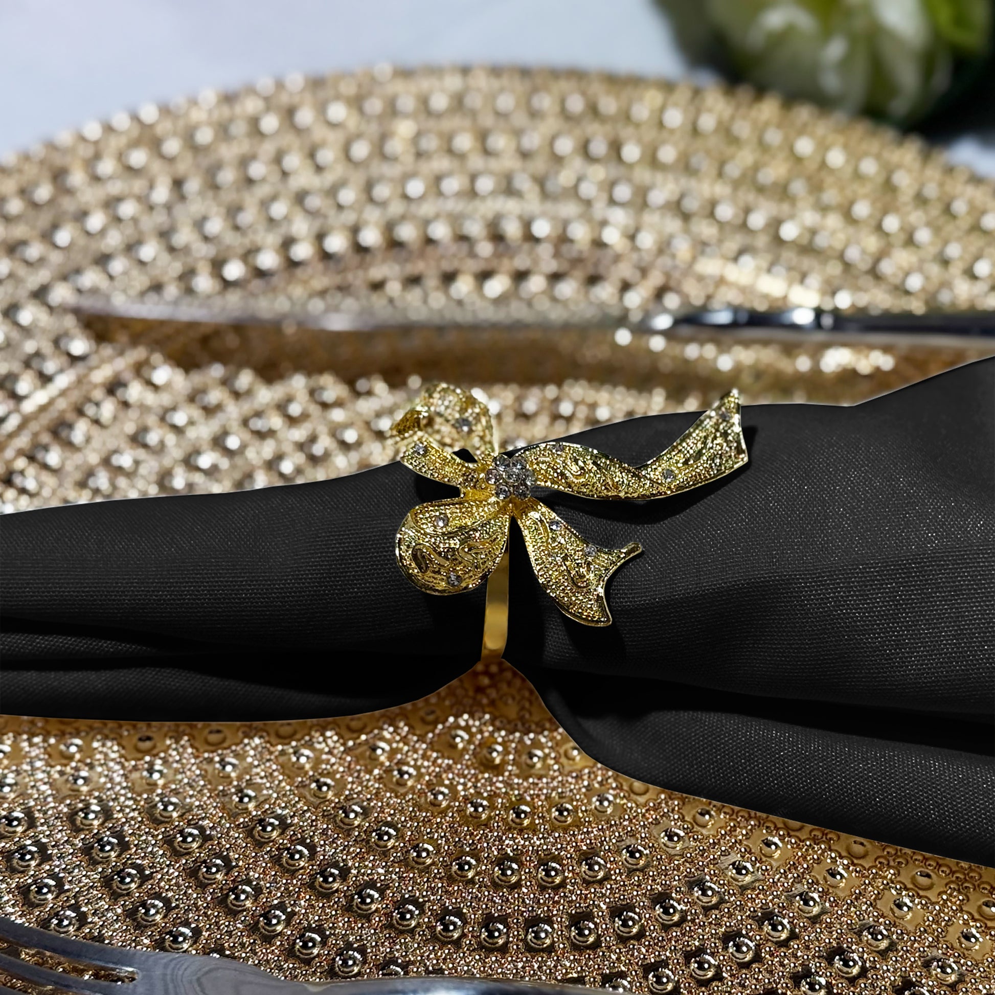 Premium Spun Polyester Napkin 20"x20" Black with a gold bow napkin ring on a gold charger plate