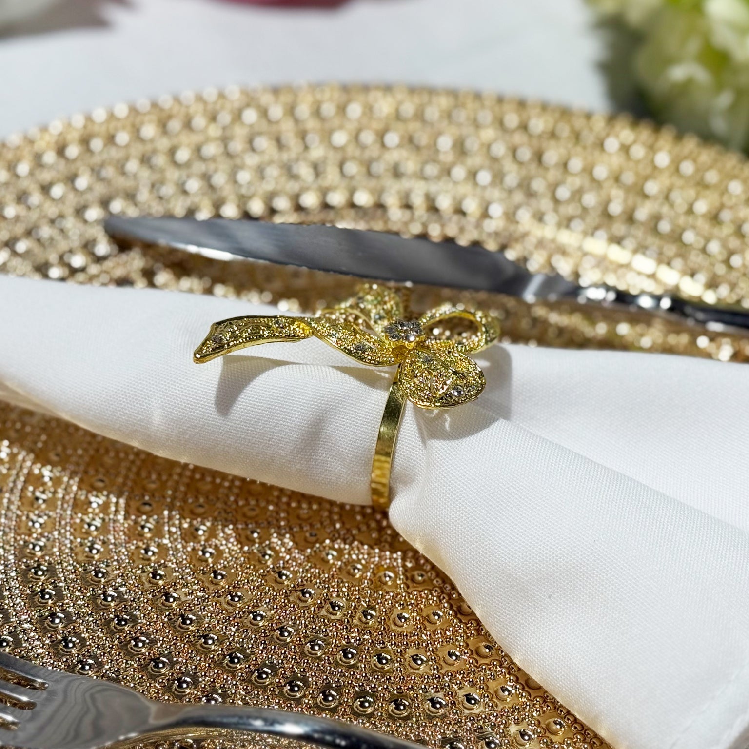 Premium Spun Polyester Napkin 20"x20" White with a gold bow napkin ring and gold charger plate