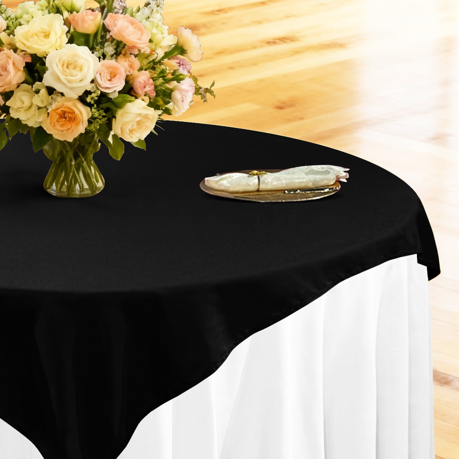 table setting with floral centerpiece, gold charger plate, ivory napkin ontop a white tablecloth 