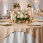 Premium Spun Polyester Square 90"x90" Overlay/Tablecloth Champagne on top a white tablecloth, with glass wine goblets, floral centerpiece, tapered candles and white charger plates