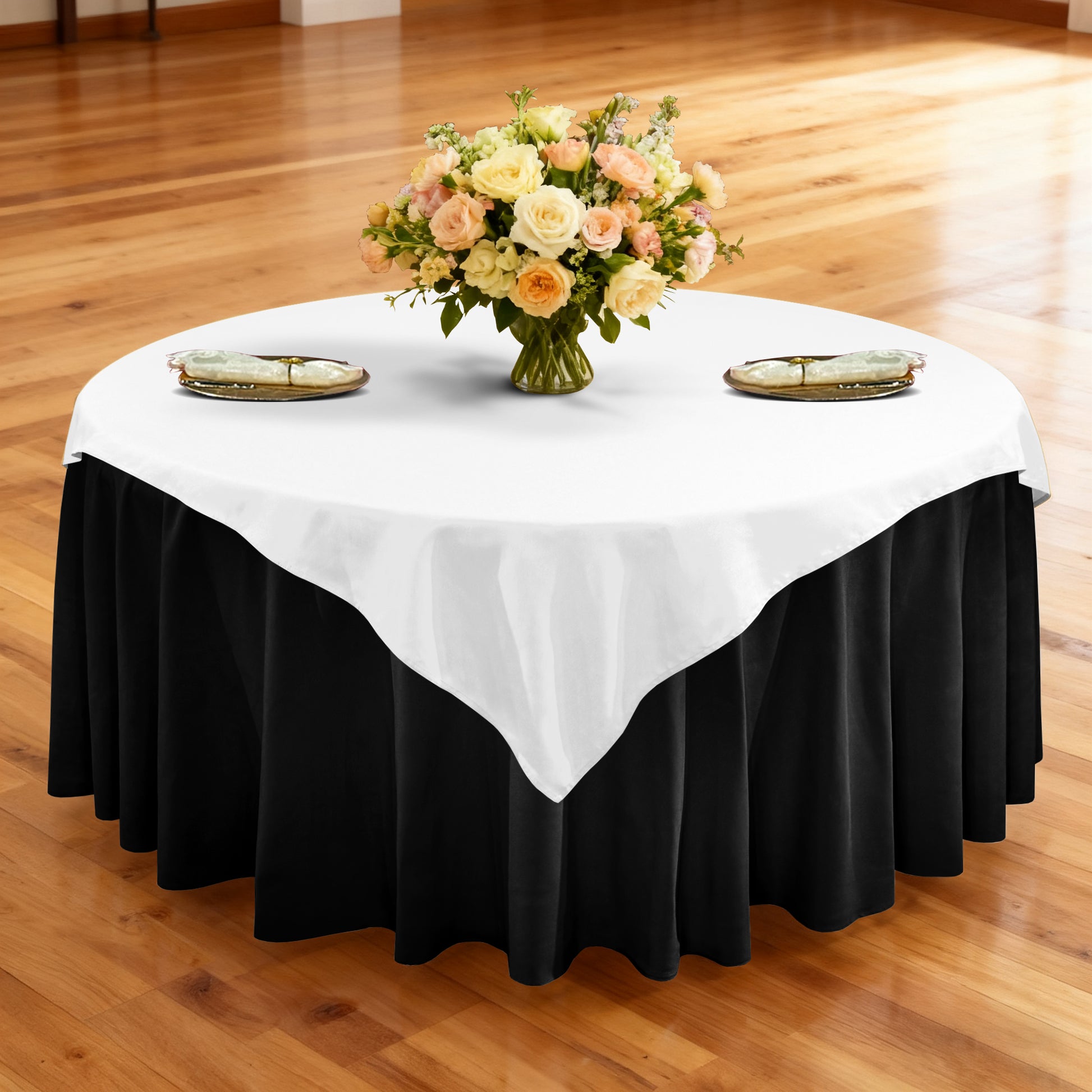 Premium Spun Polyester Square 90"x90" Overlay/Tablecloth White table setting with floral centerpiece, gold charger plates, ivory napkins ontop a black tablecloth 