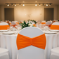 Ruffled Spandex Chair Band - Orange on top of white spandex chair cover for birthday reception