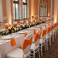 Ruffled Spandex Chair Band - Orange on top of white chair for birthday reception with orange napkin  white charger plate and dinner plate