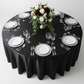 top view image of Satin 132" Round Tablecloth - Black with white plain charger plate
