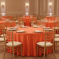 Satin 132" Round Tablecloth - Orange with gold charger plate and chiavari chairs for indoor debutante reception