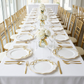 Scalloped Bow Acrylic Charger Plate Gold on top of a white tablecloth with water glasses, gold chiavari chairs, and floral centerpieces