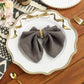Scalloped Bow Acrylic Charger Plate Gold setting with a gray napkin with a gold napkin ring, gold utensils, and florals