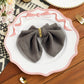 Scalloped Bow Acrylic Charger Plate Pink setting with a gray napkin with a gold napkin ring, gold utensils, and florals