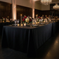Scuba King 108"x156" Rectangular Tablecloth Black paired with white and red florals, wine goblets, and tapered candles