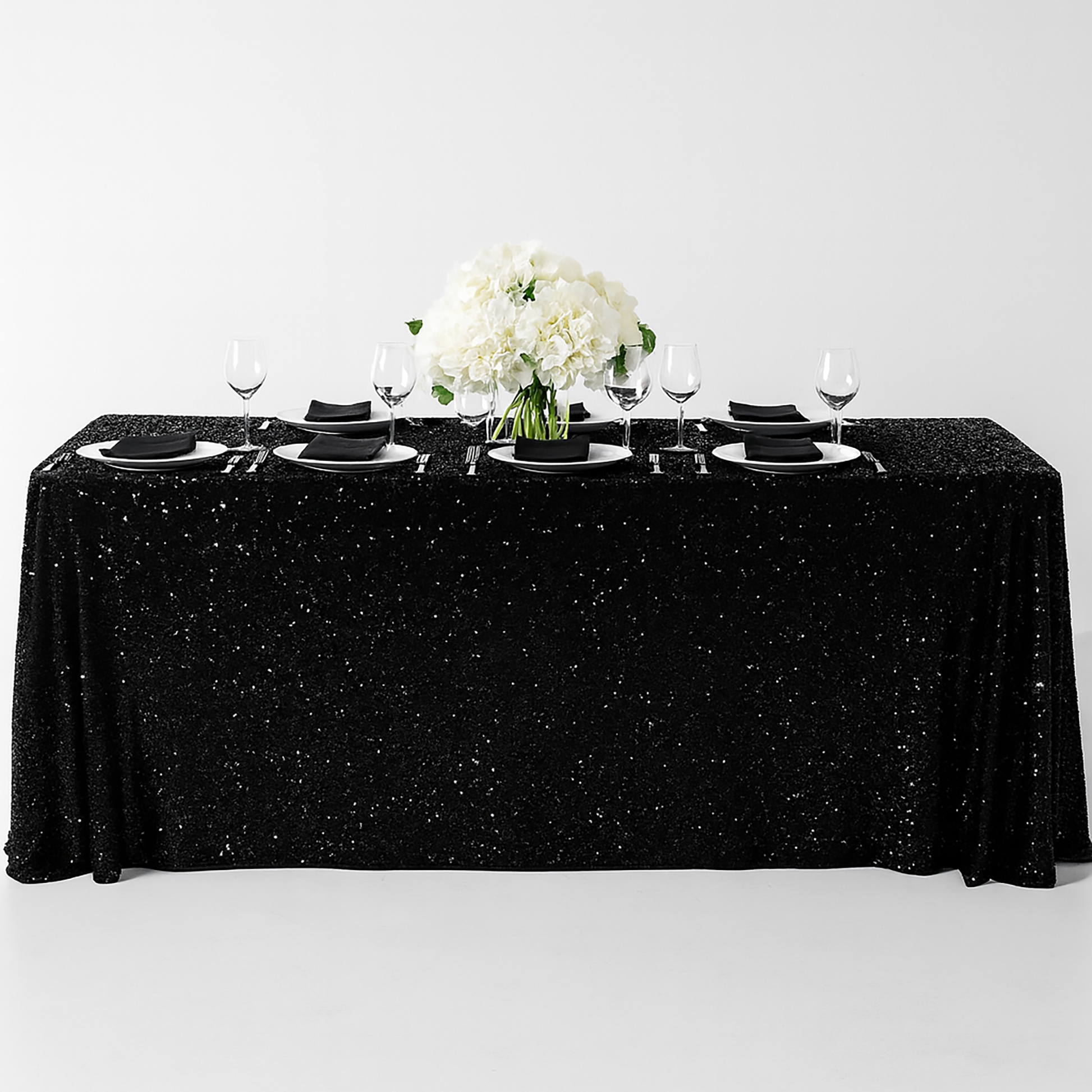 Sequin velvet black rectangular tablecloth with black napkins, white charger plates and wine goblets
