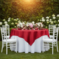Square 72" Satin Table Overlay - Apple Red on top of white round tablecloth with flower centerpieces for outdoor wedding reception
