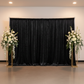 Velvet 16ft H x 52" W Drape/Backdrop Curtain Panel - Black wide angle front view with 2 centerpiece with flowers and orchids on top