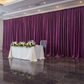 Velvet 18ft H x 52" W Drape/Backdrop Curtain Panel - Violet diagonal perspective with 50% fullness of drape at the back of white sweetheart table