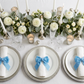 Velvet Bow Tie Napkin Ring Baby Blue  with a white napkin on top  white dinner plate and silver charger plate