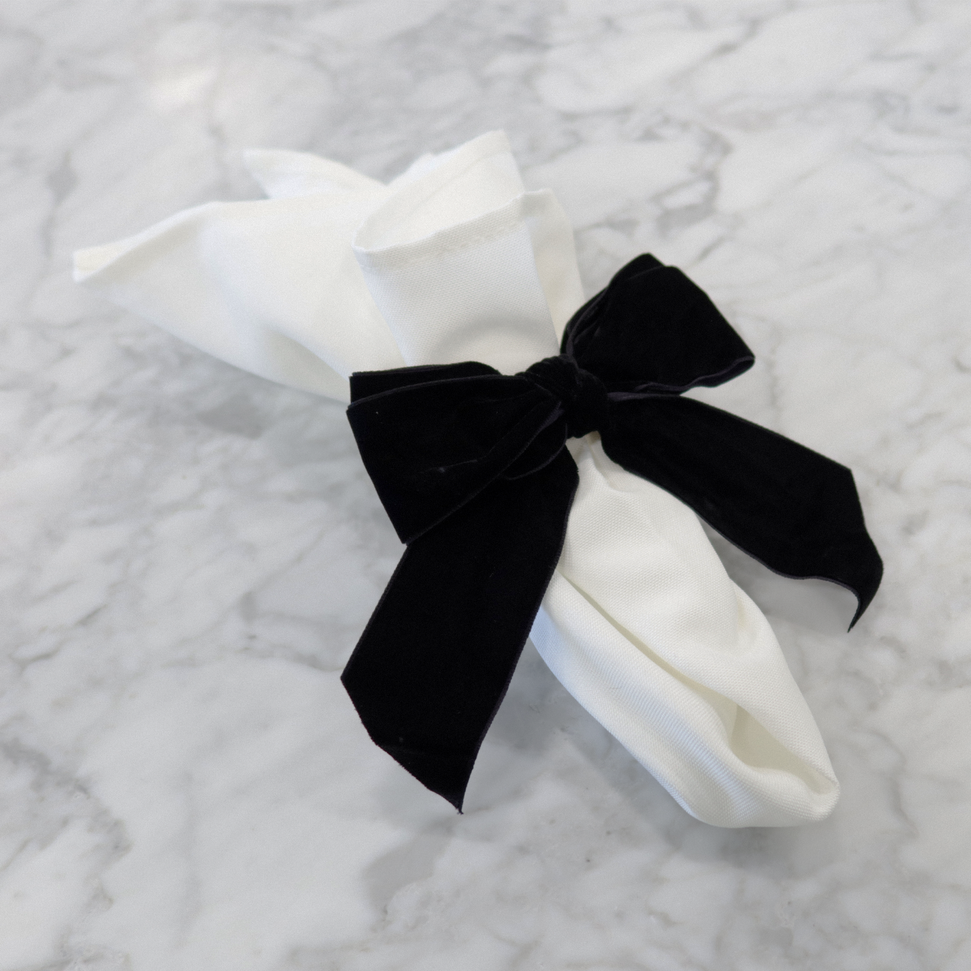 Velvet Bow-Tie Napkin Ring Black on a white polyester napkin