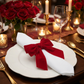 Velvet Bow-Tie Napkin Ring Red on a white napkin on top a white dinner plate