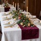 reception table with the Velvet Table Runner Cabernet  on top a white tablecloth, white gold trimmed dinner plates, tapered candles and greenery centerpiece