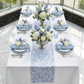 birdseye view Vintage Lace Print Scuba Table Runner Dusty Blue/White on a rectangular table with dusty blue napkins and blue and white floral centerpieces