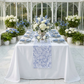 Vintage Lace Print Scuba Table Runner Dusty Blue/White on a rectangular table with dusty blue napkins and blue and white floral centerpieces