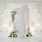 White Telephone Booth Printed Backdrop Spandex Cover paired with floral, balloons, and white backdrop with LED lights