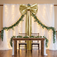 XL Giant Fabric Bow for Backdrop - Metallic Gold with sheer voile white drapes  and eucalyptus greenery garland
