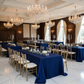 Grand hotel ballroom with navy blue pintuck tablecloth on 6ft rectangular tables