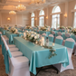 Indoor banquet hall teal tablecloths with centerpiece displays