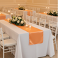 Indoor banquet hall with orange satin table runner