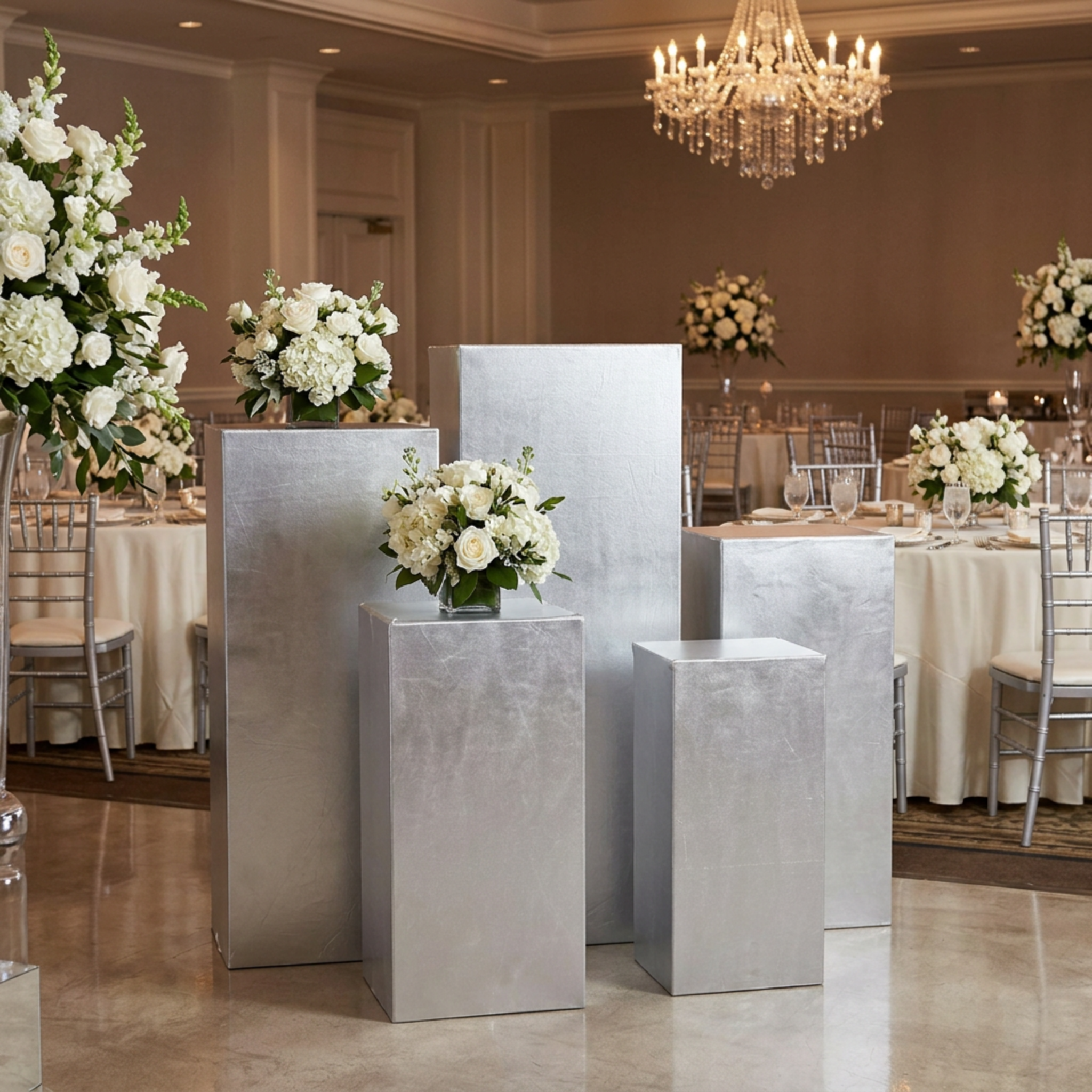 Silver pedestal covers in an indoor wedding ballroom