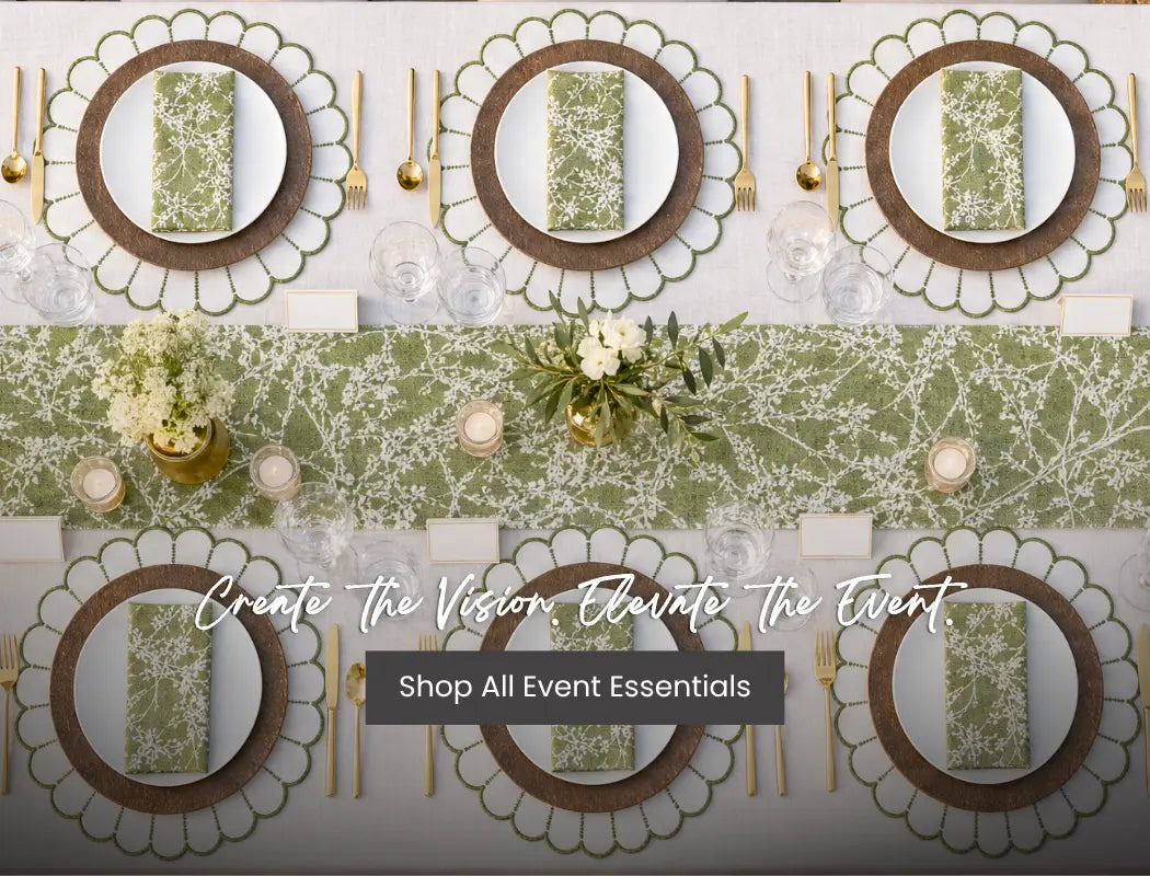 Top-down view of an event table setting with green napkins, brown chargers, gold cutlery, glassware, and floral centerpiece.