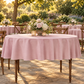 Outdoor garden with matching dusty rose tablecloths on turned spindle-leg tables, low side angle