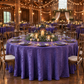 Rustic barn reception scene with purple crinkle shimmer tablecloth on a large round table