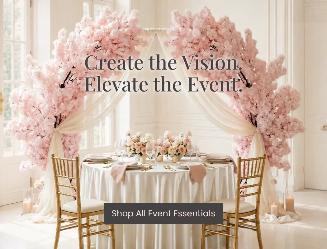 Elegant wedding reception table with pink blossom arch, ivory drapes, gold chairs, and candles for Event Essentials.