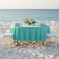 Turquoise round tablecloth as table topper with full table legs visible at beach wedding reception